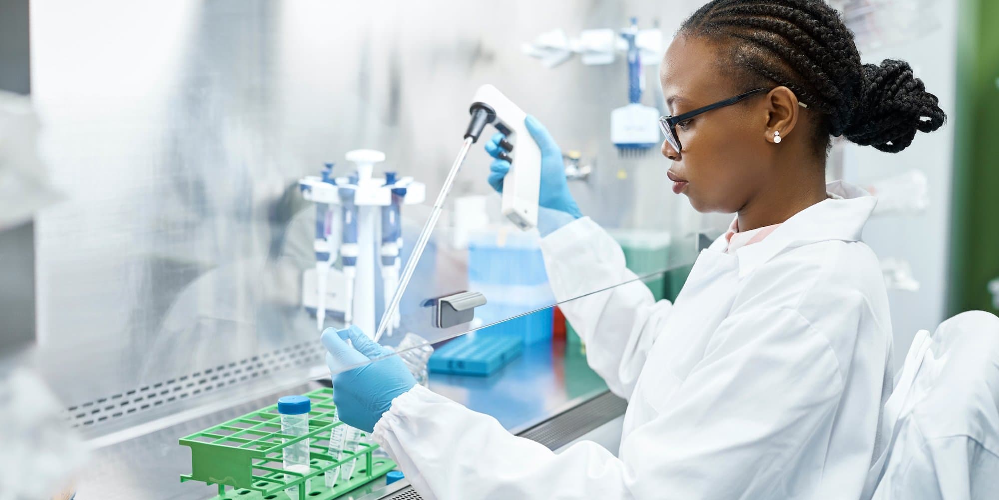 person pipetting under a laboratory hood