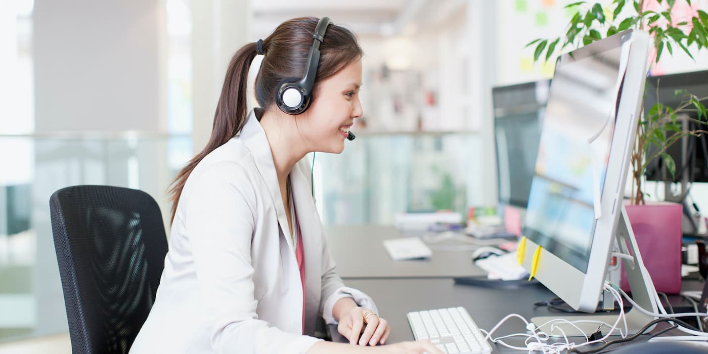 person wearing a headset sitting at a desk while working on a computer