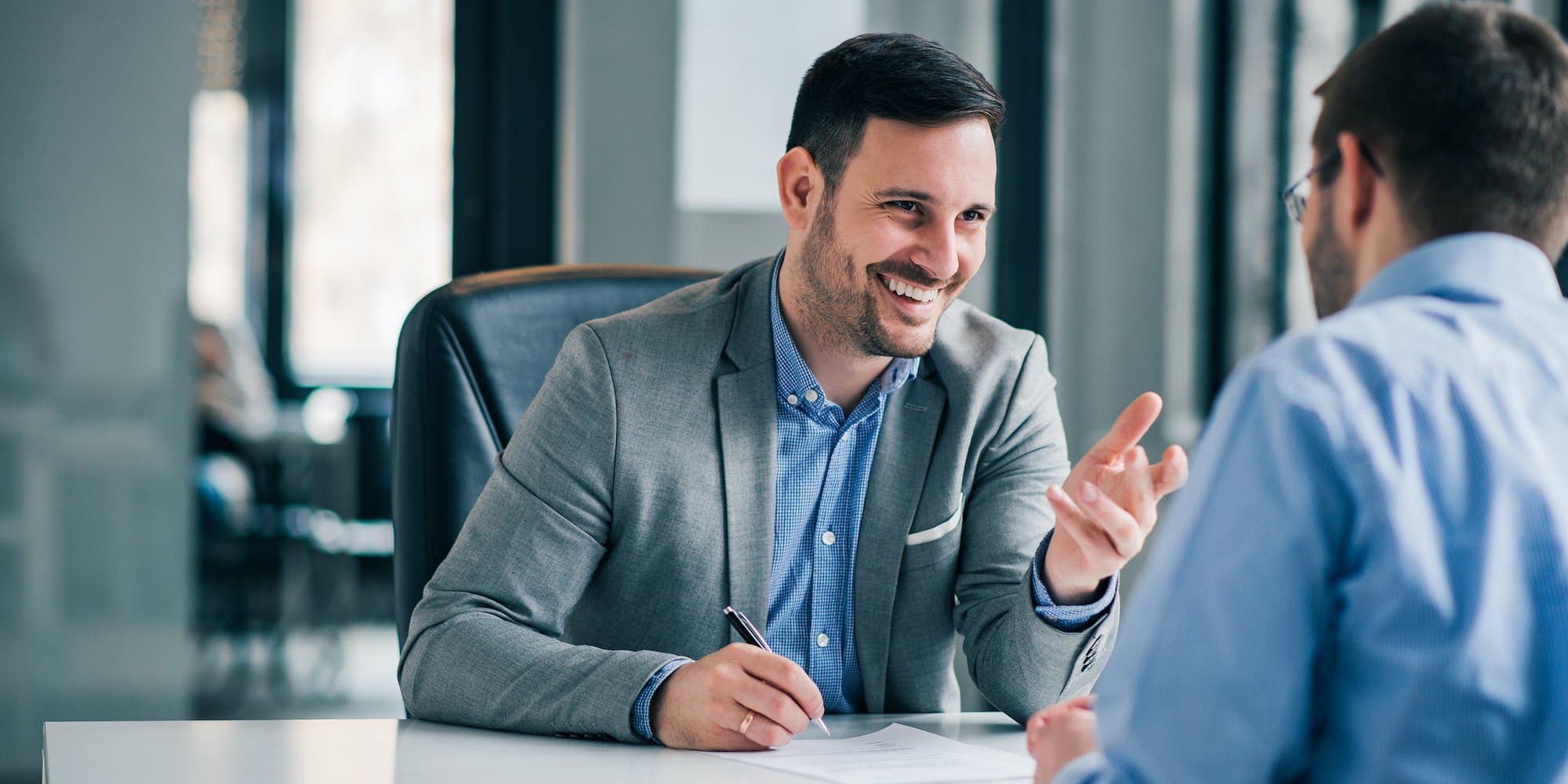 two people talking across a table in an office during a job interview