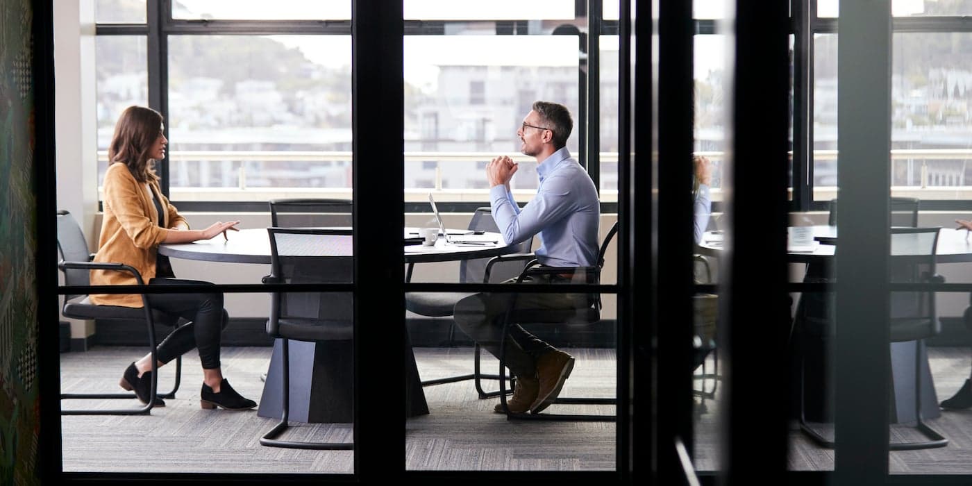 two people speaking in a conference room during a job interview