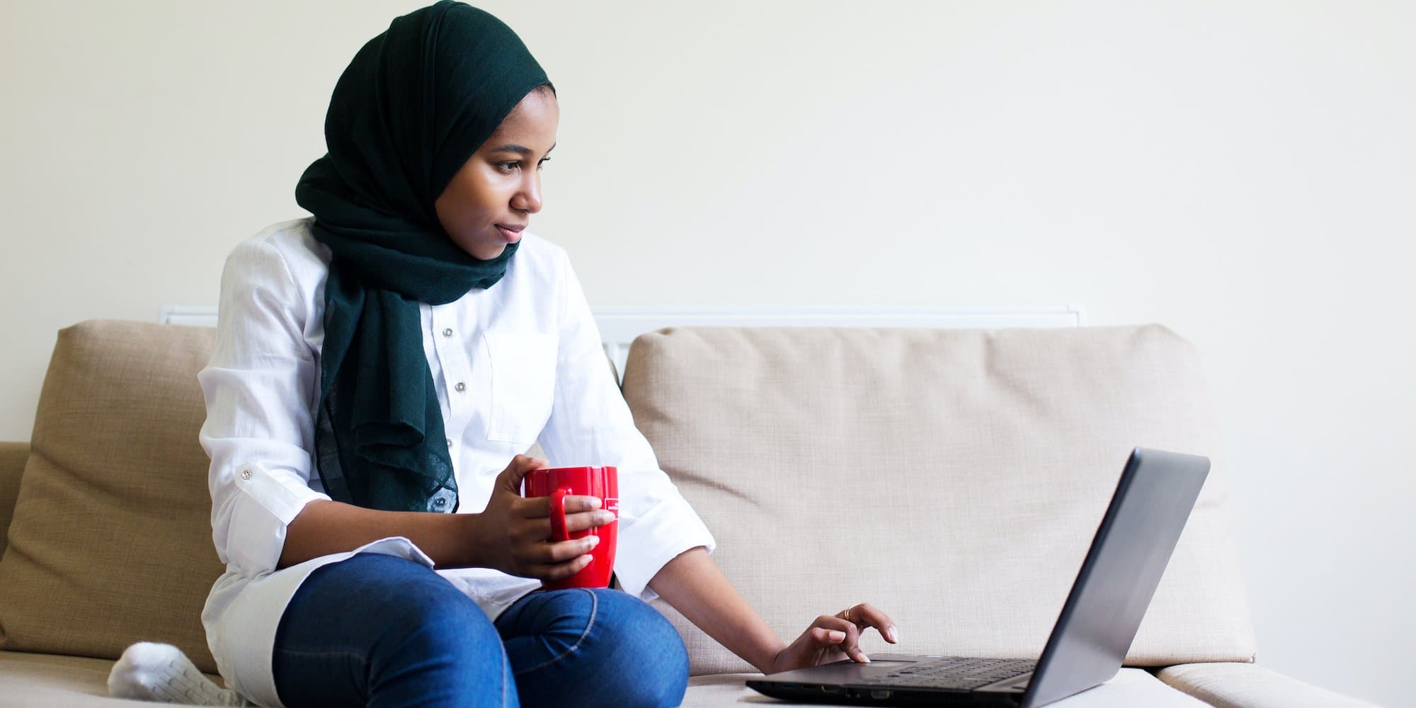 person on couch reading from laptop