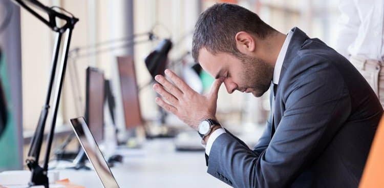 frustrated person leaning over their desk