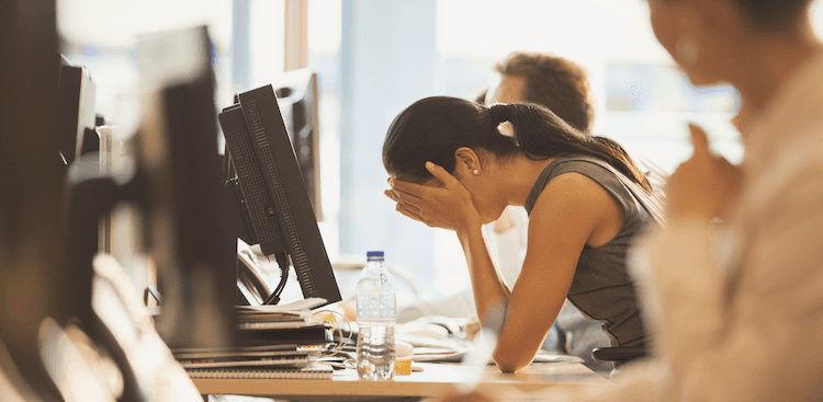 person with head in hands in an office