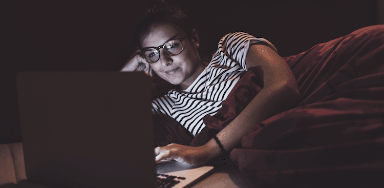 person looking at a laptop screen in bed