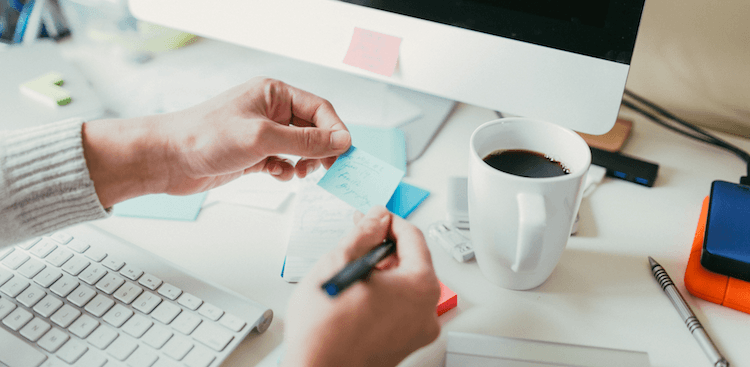 person at desk reading post it note