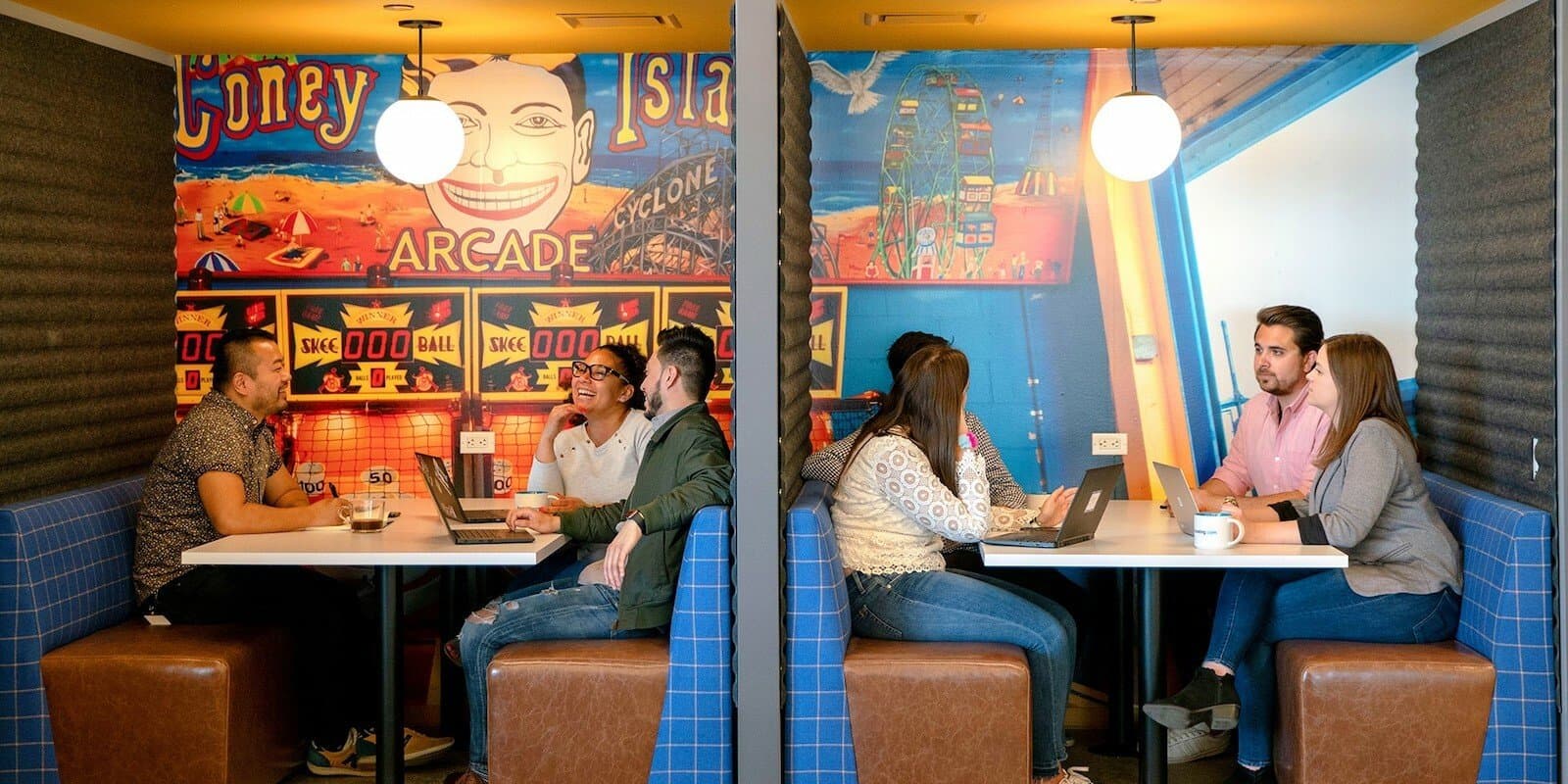 Employees sitting in booths with their laptops