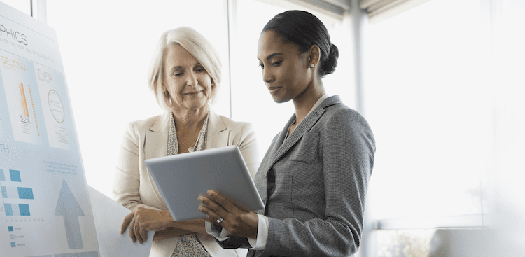 person showing a more senior colleague something on a tablet