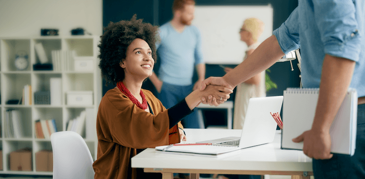 person shaking hands with co-worker at the office