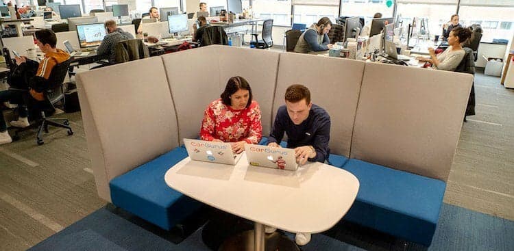 two CarGuru employees working on their laptops in the Cambridge office