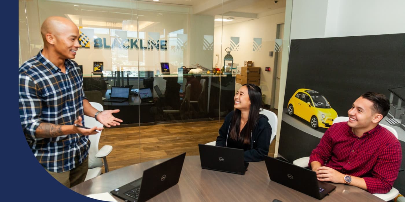 Three BlackLine employees discussing work with their laptops out.