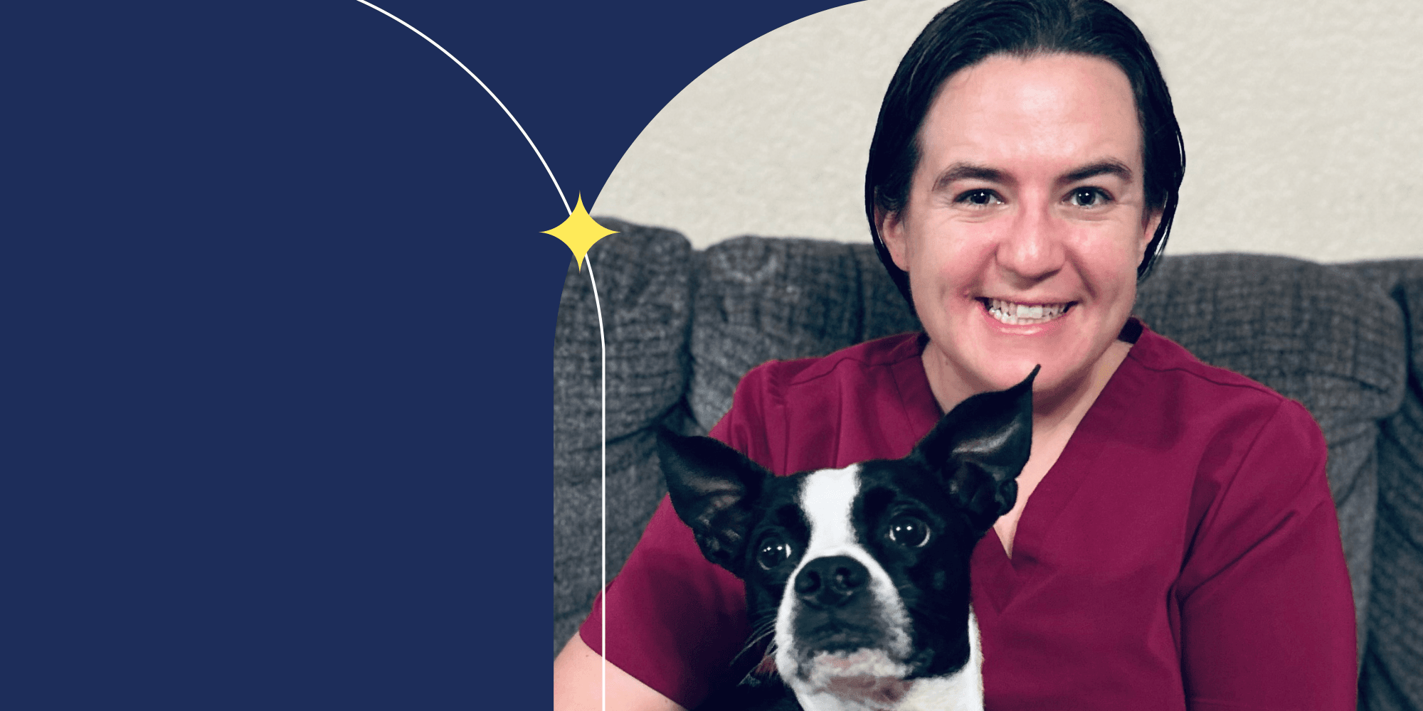 A smiling person dressed in cranberry-colored scrubs. A black-and-white dog sits in their lap.