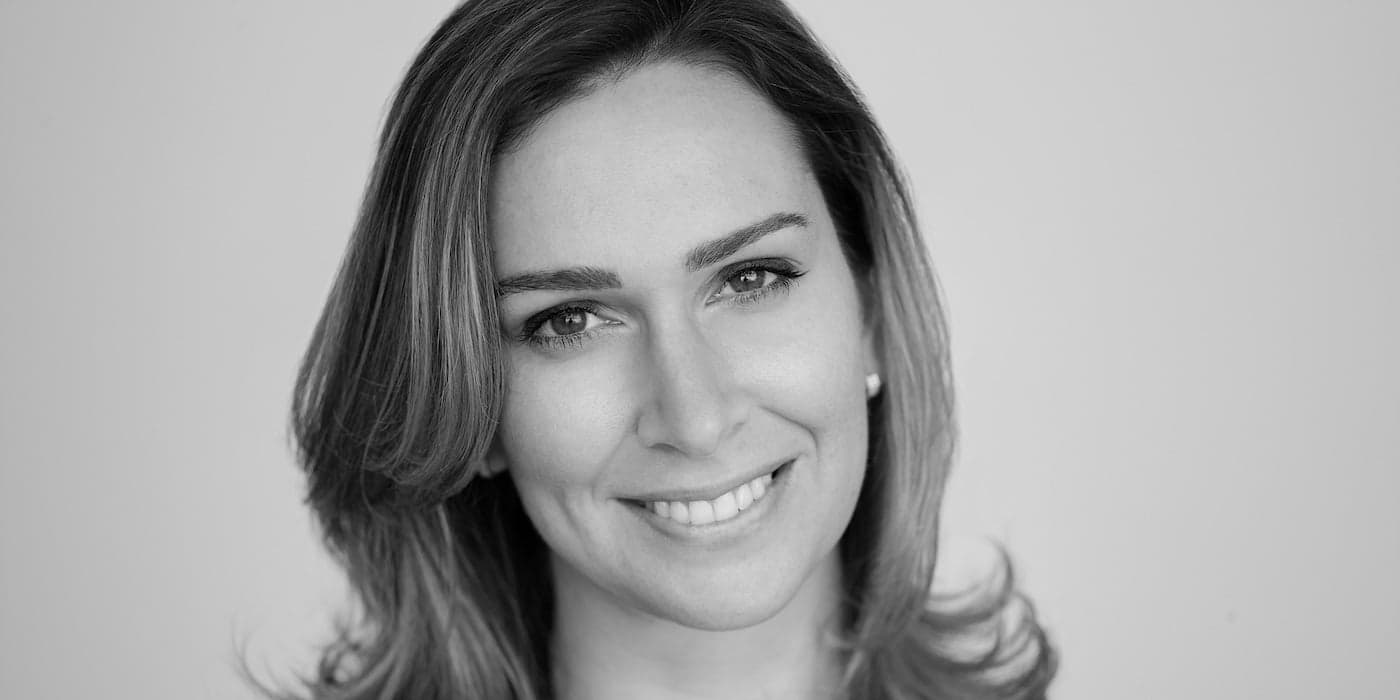 black-and-white portrait of person with shoulder-length hair smiling