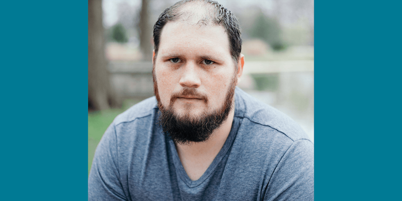 person with beard and gray T-shirt sitting outside