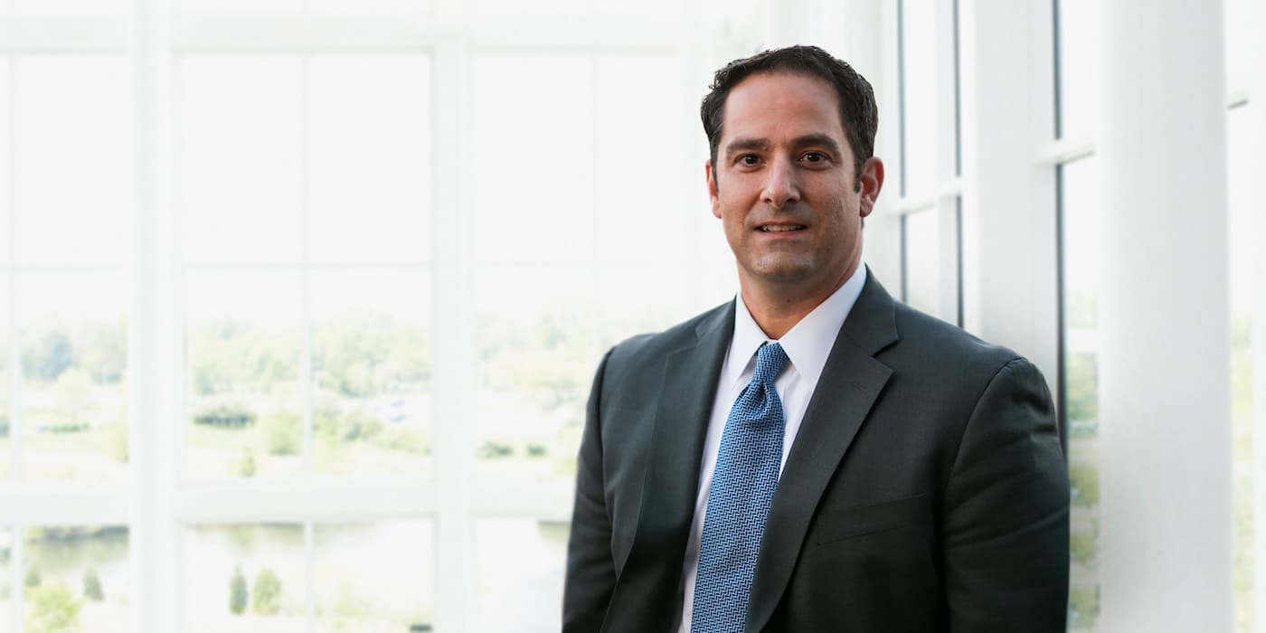 person standing by a window wearing a suit and tie