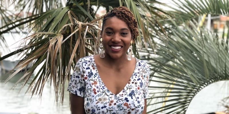 person wearing a flower-print dress standing in front of trees