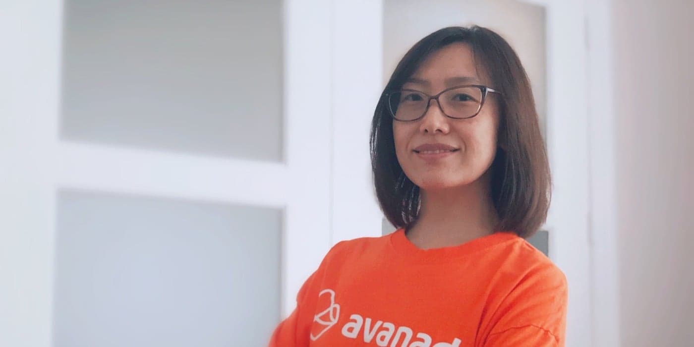 a person with shoulder-length hair and glasses wearing an orange T-shirt