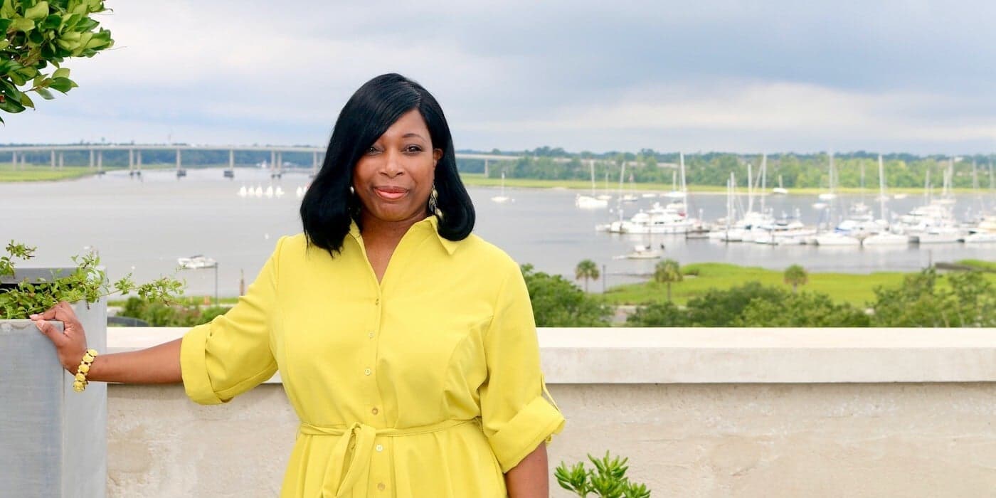 person with a yellow dress standing in front of a boat-filled harbor