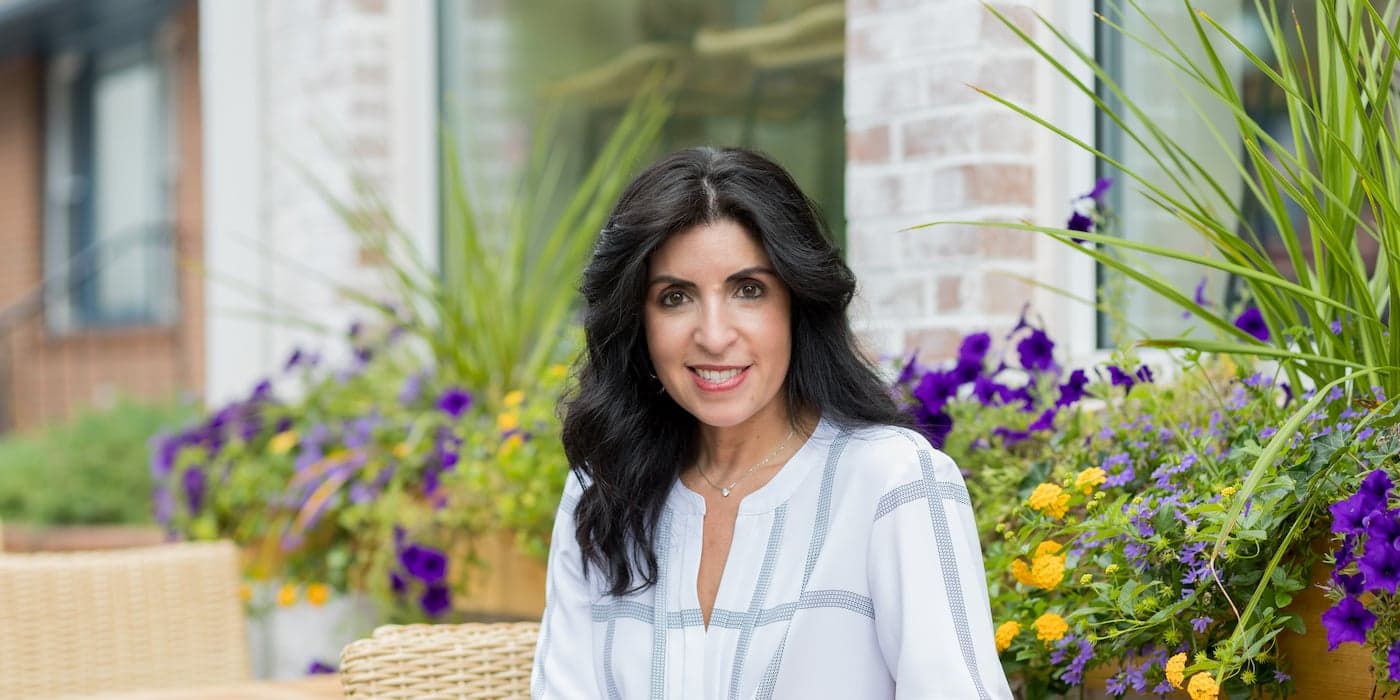 person with long black hair sitting in a garden