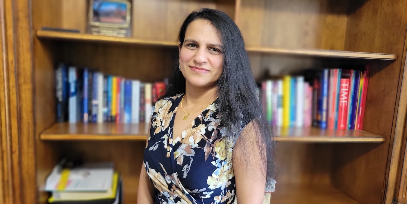 person with long hair standing in front of a bookshelf