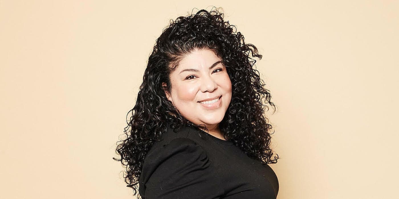 smiling person with dark curly hair and a black shirt