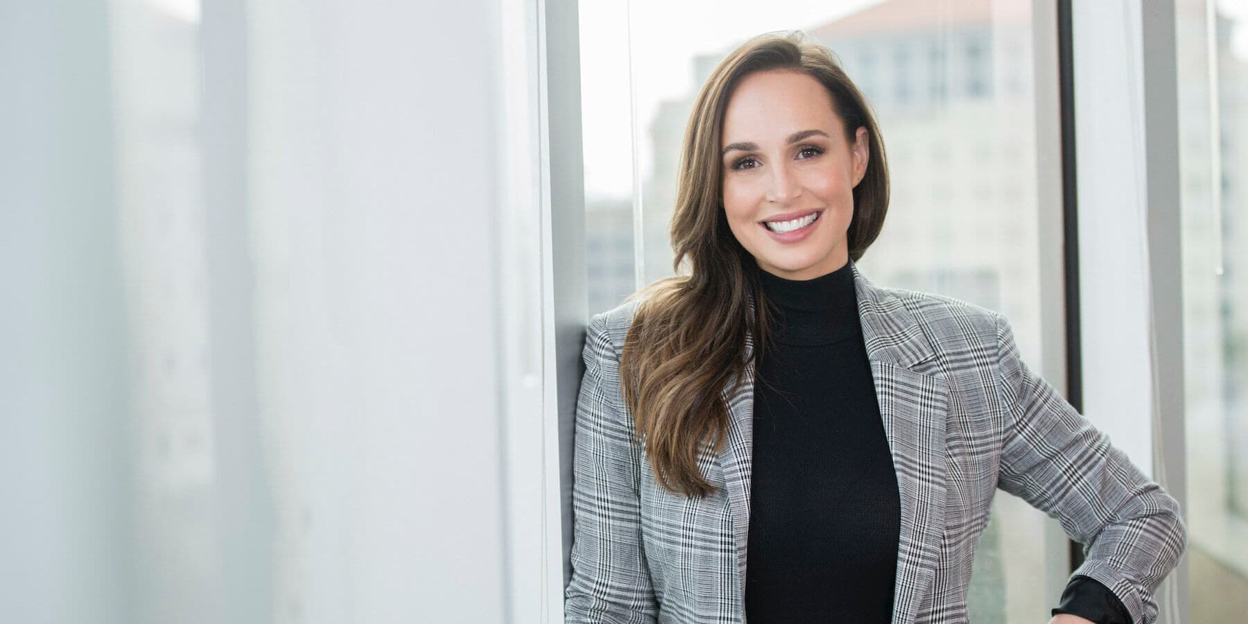 A person with long brown hair smiling in an office