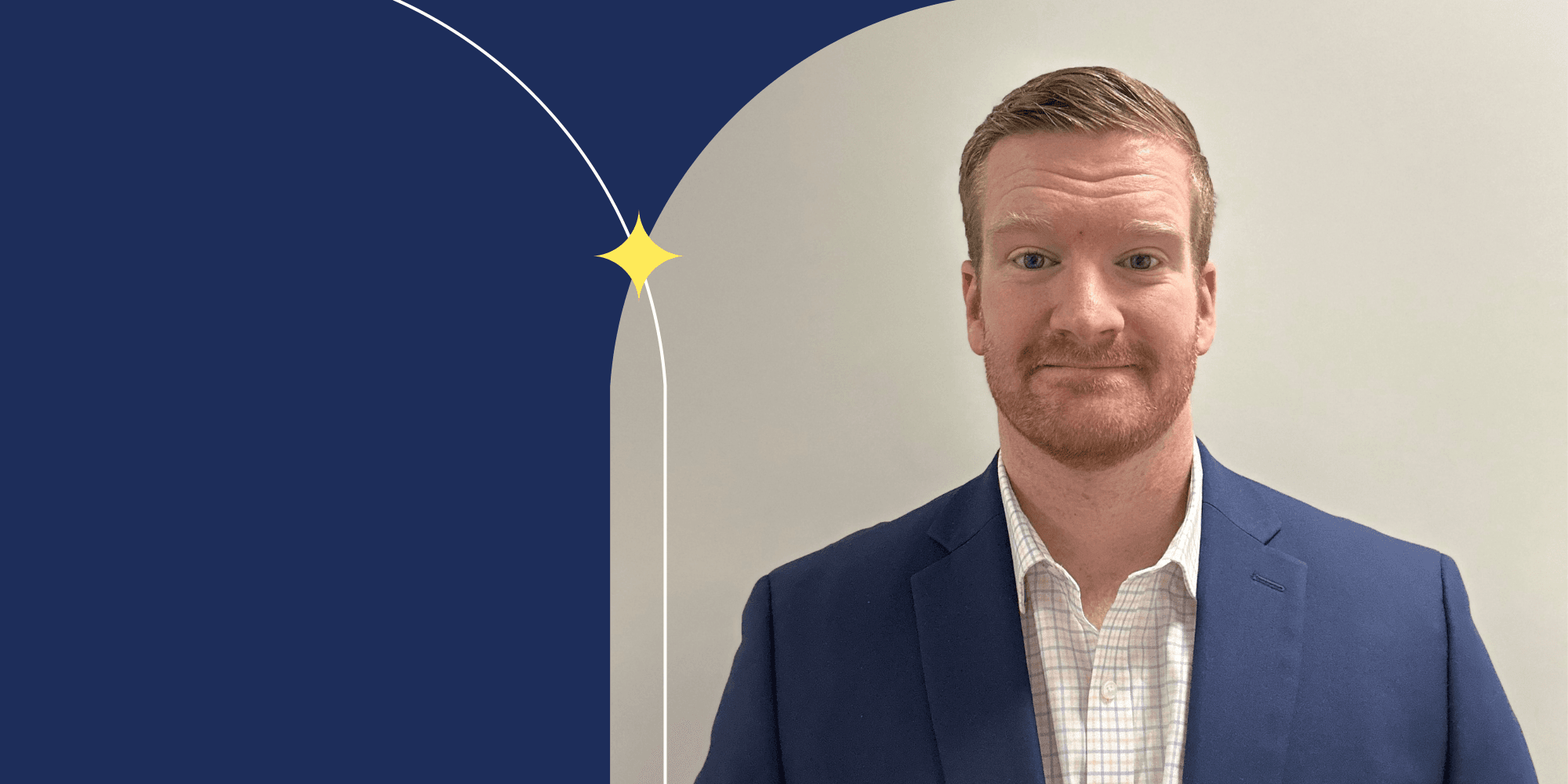 A person facing the camera. They are wearing a blue blazer and a white collared shirt. They have short blond hair and blue eyes.