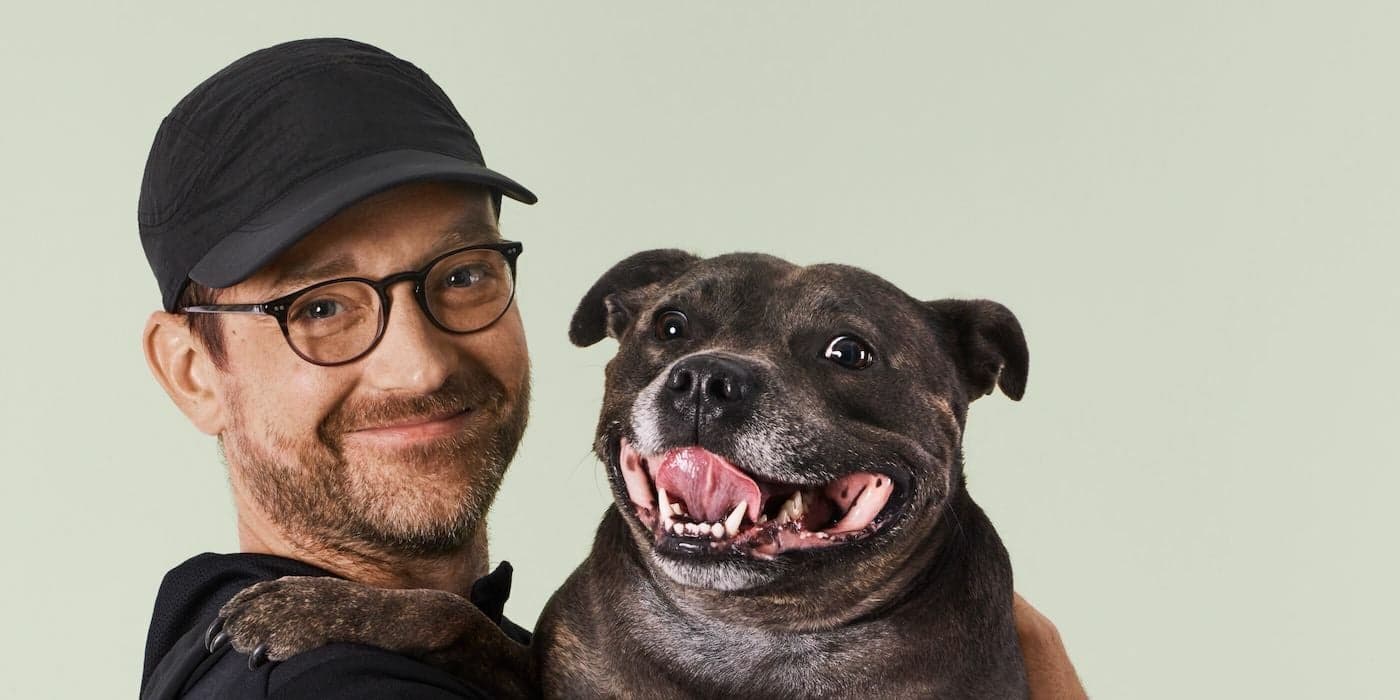 person wearing a black baseball cap and holding a dog