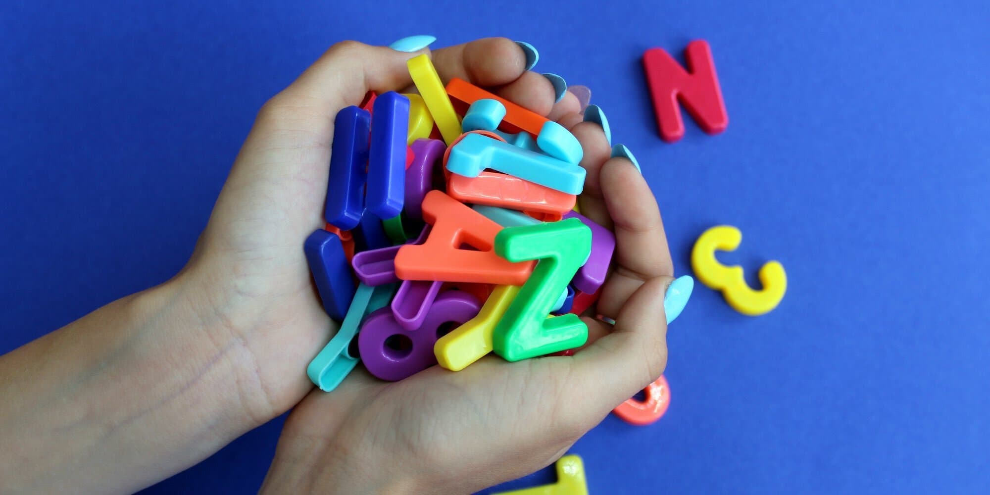 hands cupped and holding ABC magnets against a blue background