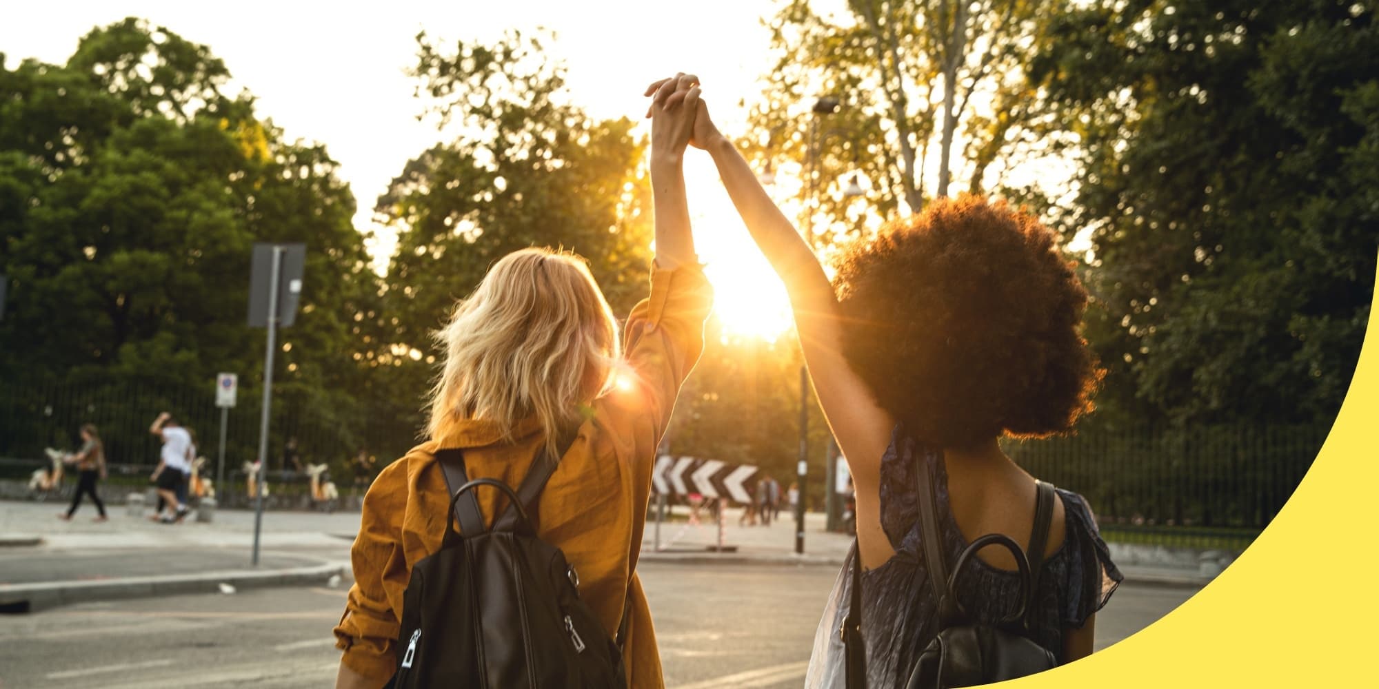two people facing away and holding hands above their heads while looking at the sunset