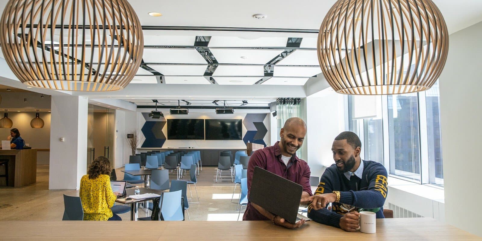 An employee showing a colleague something on their laptop screen
