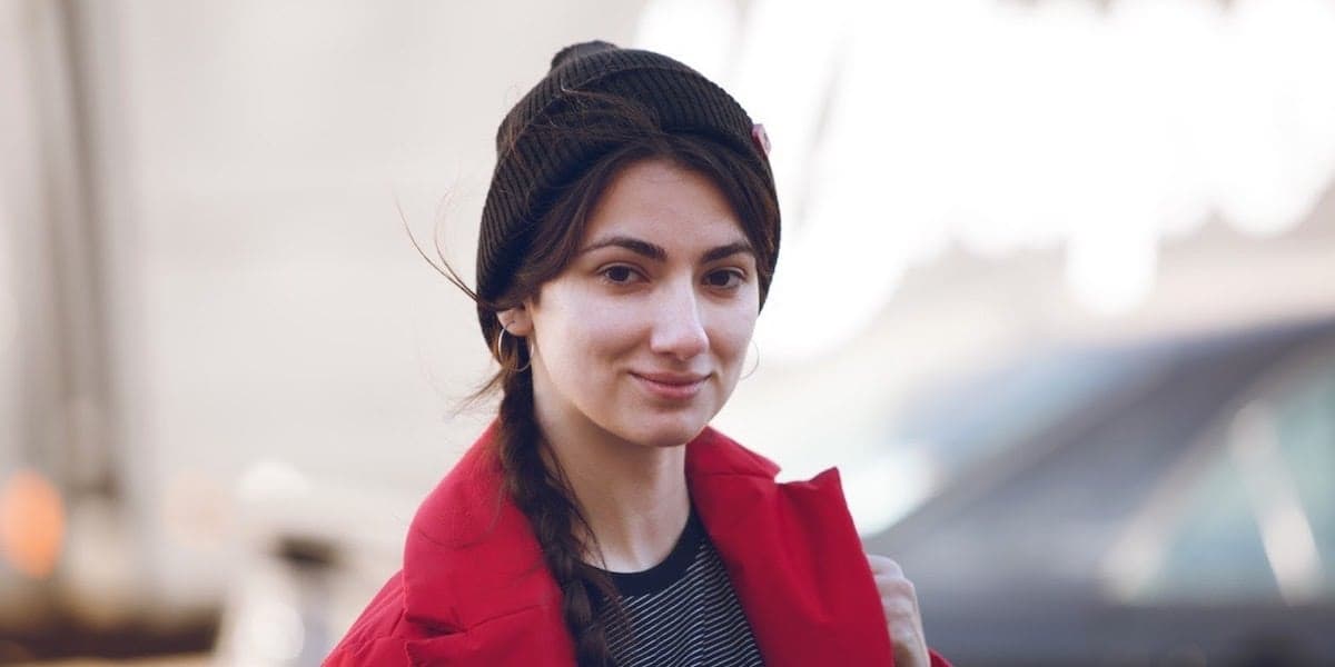 person standing outside wearing a red coat and brown winter hat