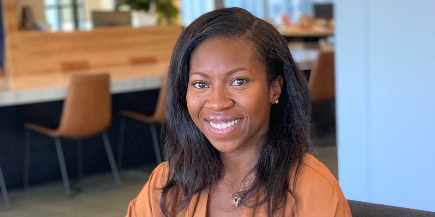 smiling person with shoulder-length hair sitting in an office