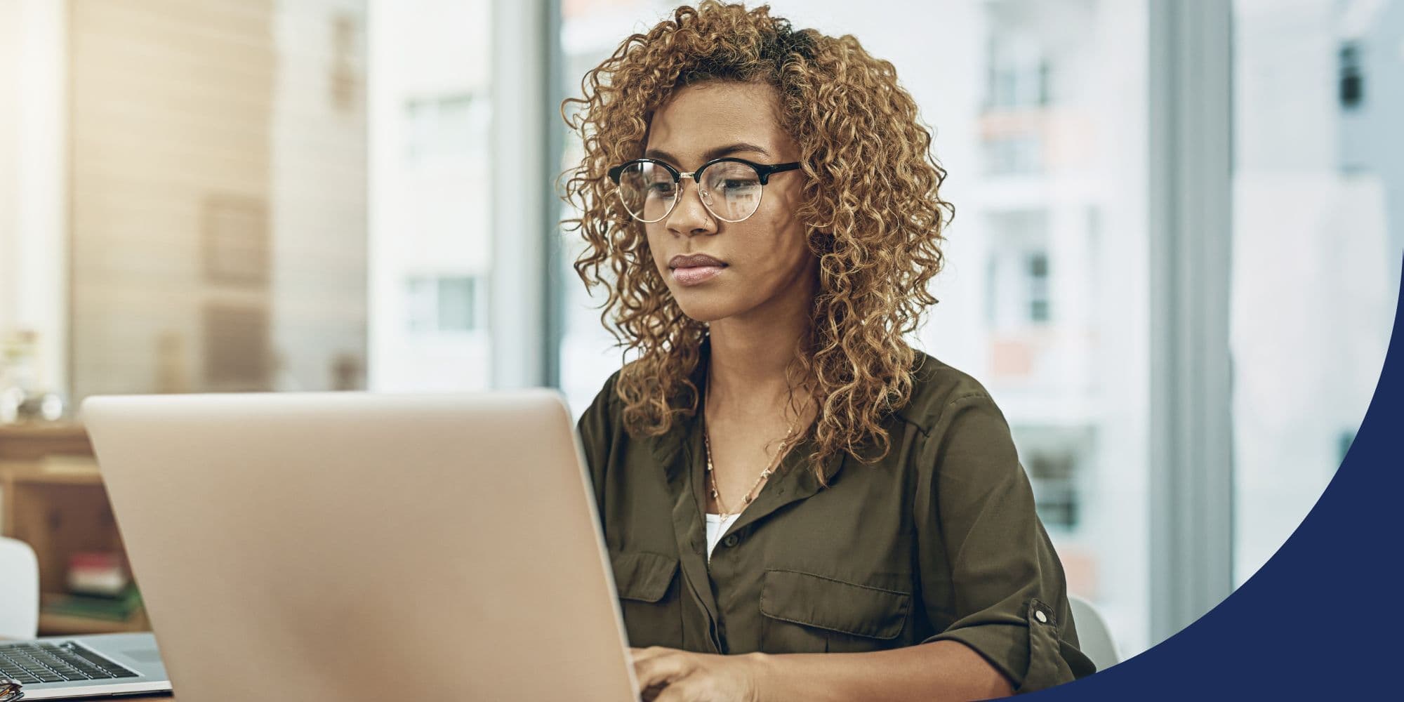 person sitting in an office typing on a laptop